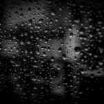 Epilepsia Close-up of raindrops on a glass surface with a dark background, creating an abstract and moody effect.