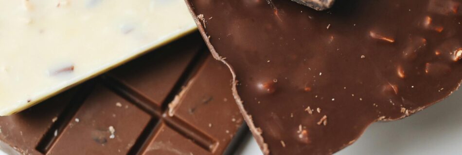 A stack of delectable dark, milk, and white chocolate bars on a white surface.